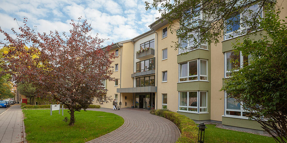 Ansicht eines DRK-Gebäudes mit großzügigem Garten, Rasenfläche und Kiesweg im Vordergrund.